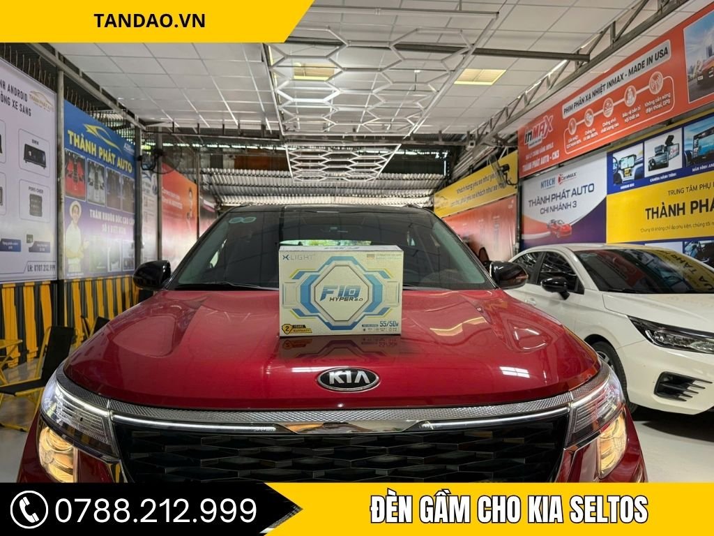  Chiếc xe Kia Seltos màu đỏ đang đỗ trong gara của Thành Phát Auto. Trên nắp capo có hộp sản phẩm đèn gầm X-Light F10 Hyper 2.0.