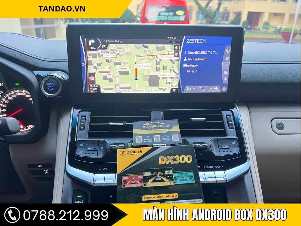 Ảnh màn hình ô tô đang sử dụng Android Box DX300 Cho Land Cruiser hiển thị bản đồ 3D chỉ đường chi tiết. Phía dưới là hộp sản phẩm DX300 Android Box thế hệ 2, kèm thẻ bảo hành của Thành Phát Auto